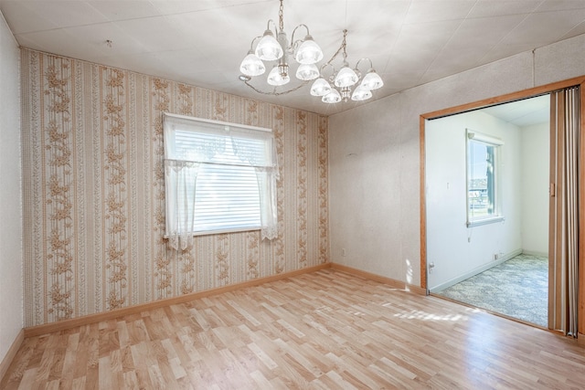unfurnished room featuring plenty of natural light, a chandelier, and wood finished floors