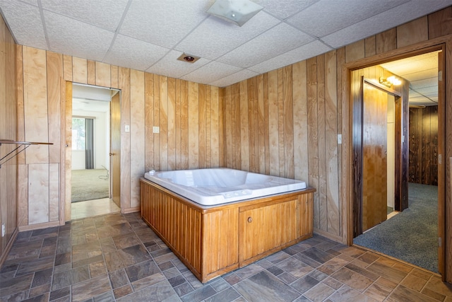 misc room featuring a paneled ceiling, stone finish floor, and wood walls