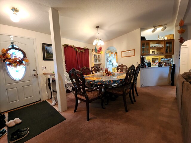 dining room with an inviting chandelier and dark colored carpet