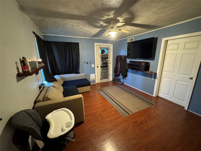 living room with ornamental molding, wood-type flooring, ceiling fan, and a textured ceiling