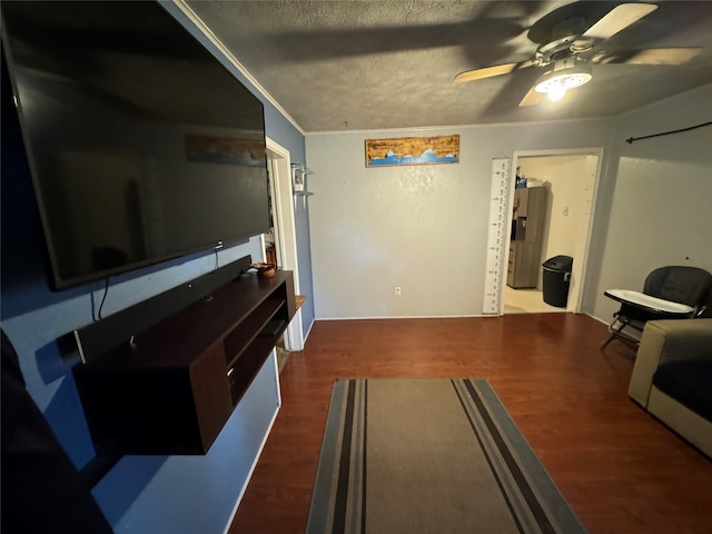 living room featuring ornamental molding, ceiling fan, dark hardwood / wood-style floors, and a textured ceiling