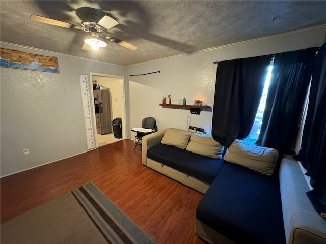 living room with ceiling fan, a textured ceiling, crown molding, and wood-type flooring