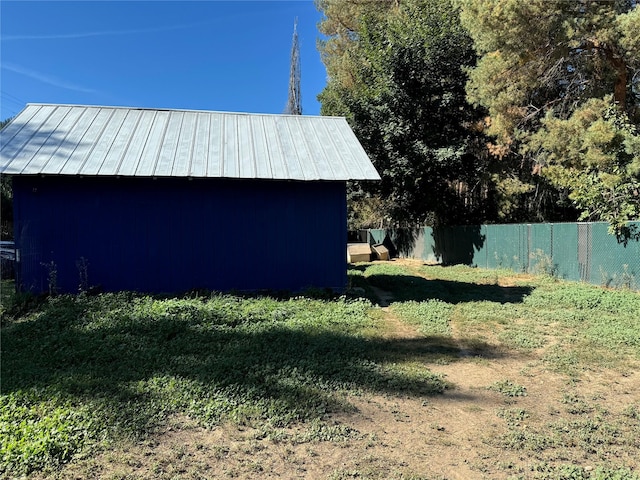 view of yard featuring a storage shed, fence, and an outdoor structure