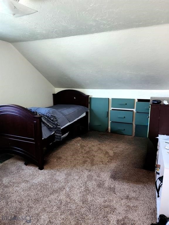 bedroom with lofted ceiling, carpet, and a textured ceiling