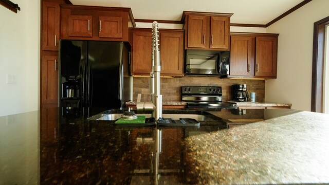 kitchen with dark stone counters, black appliances, backsplash, and crown molding