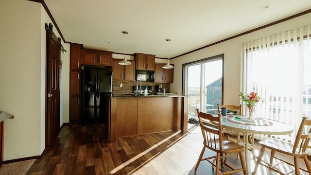 kitchen with tasteful backsplash, a barn door, black appliances, decorative light fixtures, and dark hardwood / wood-style flooring