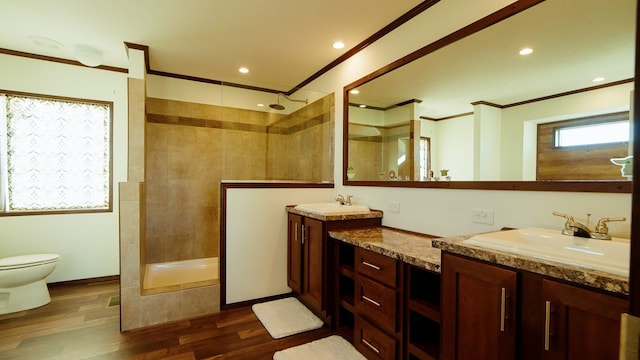 bathroom with vanity, toilet, ornamental molding, tiled shower, and hardwood / wood-style floors