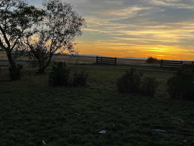 yard at dusk featuring a rural view