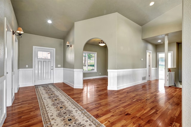 foyer entrance featuring lofted ceiling, hardwood / wood-style floors, and radiator heating unit