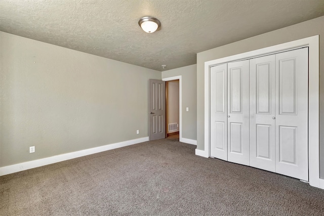 unfurnished bedroom featuring dark carpet, a textured ceiling, and a closet