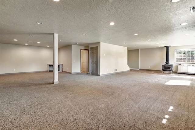 interior space with a textured ceiling, a wood stove, and light colored carpet