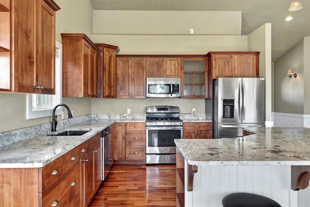 kitchen with light stone counters, a kitchen bar, stainless steel appliances, and dark hardwood / wood-style flooring