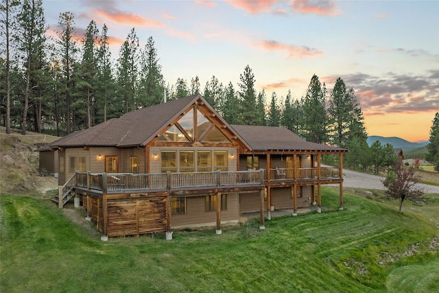 back house at dusk with a lawn and a deck