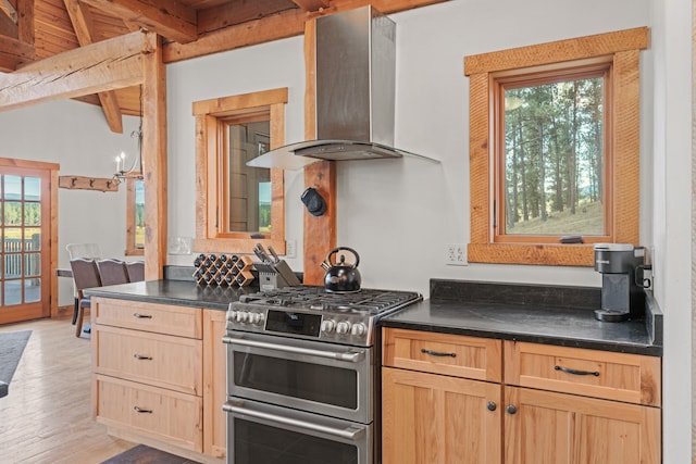 kitchen with a healthy amount of sunlight, light wood-type flooring, wall chimney range hood, and double oven range