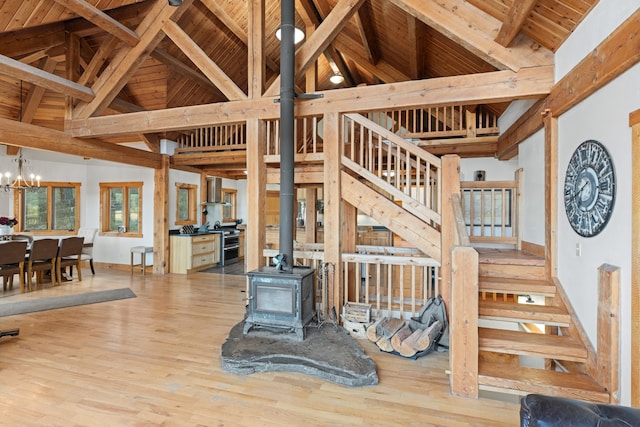 interior space featuring high vaulted ceiling, a wood stove, wooden ceiling, wood-type flooring, and an inviting chandelier