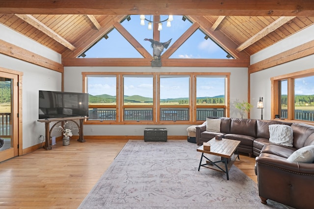 living room with beamed ceiling, light wood-type flooring, high vaulted ceiling, and a healthy amount of sunlight