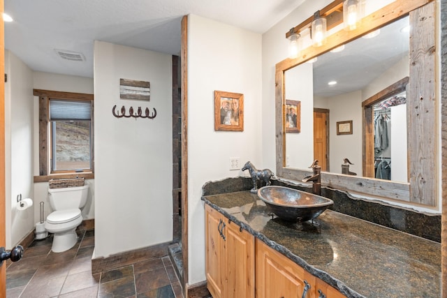 1200 Shaw Ln, Bonner, MT 59823 - bathroom with toilet, vanity, baseboards, and stone finish flooring