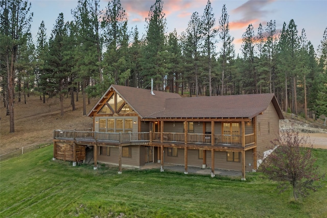 back house at dusk featuring a yard and a deck