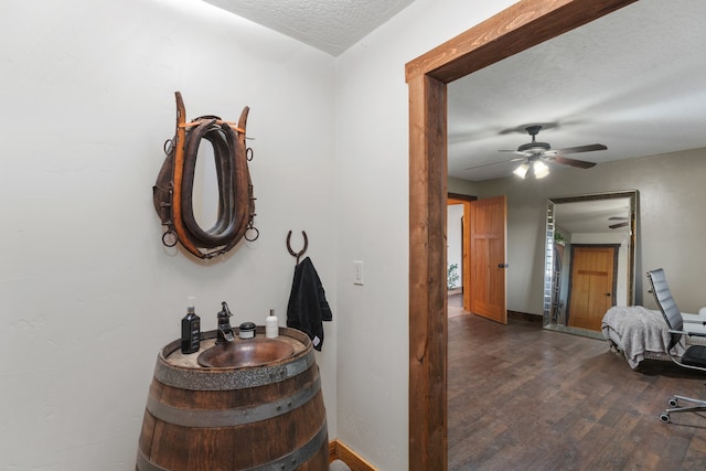 hallway with a textured ceiling and dark hardwood / wood-style flooring