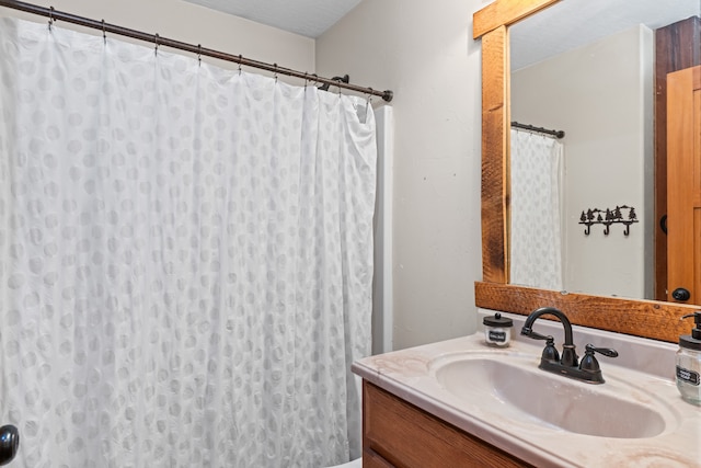 bathroom featuring vanity, a textured ceiling, and curtained shower