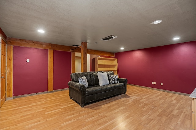 cinema room with light hardwood / wood-style floors and a textured ceiling