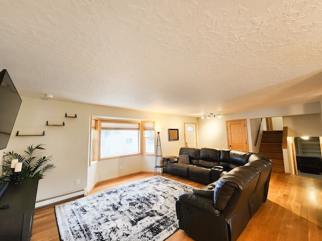 living room featuring a baseboard radiator, a textured ceiling, and light hardwood / wood-style flooring