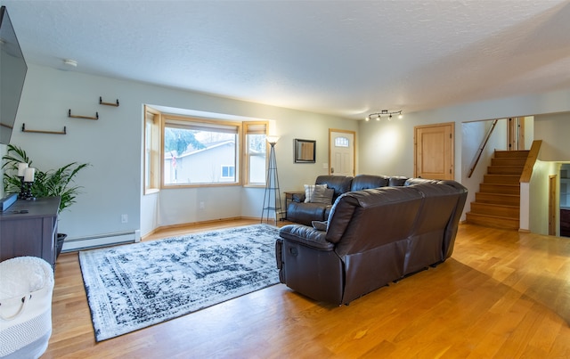 living room featuring a textured ceiling, light hardwood / wood-style flooring, and a baseboard radiator