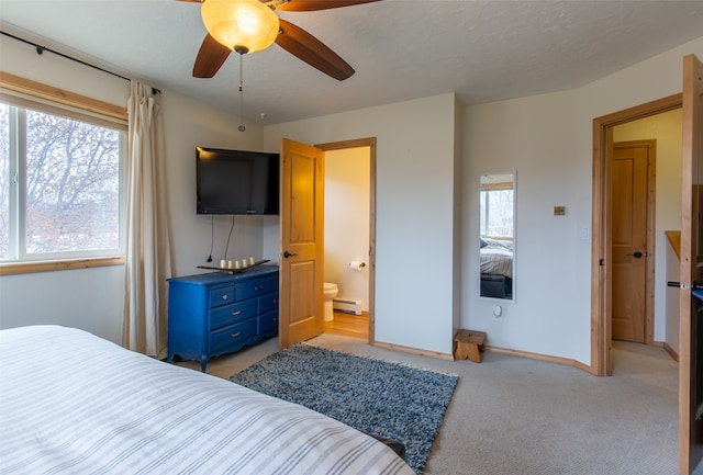 carpeted bedroom with a baseboard heating unit, ceiling fan, multiple windows, and connected bathroom