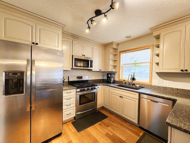 kitchen with appliances with stainless steel finishes, cream cabinetry, light hardwood / wood-style floors, and sink