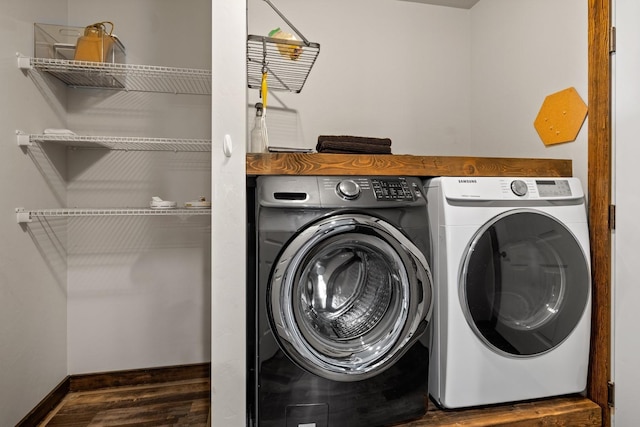 laundry area featuring separate washer and dryer, baseboards, wood finished floors, and laundry area