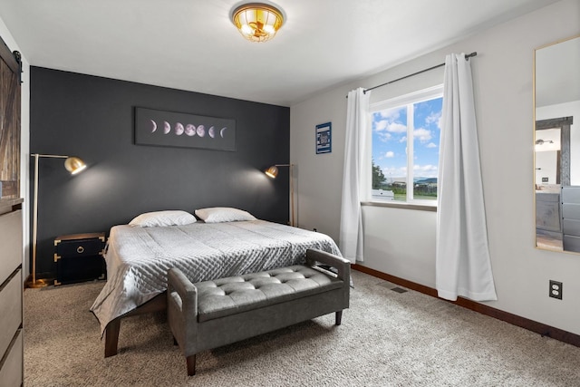 carpeted bedroom with a barn door, visible vents, and baseboards