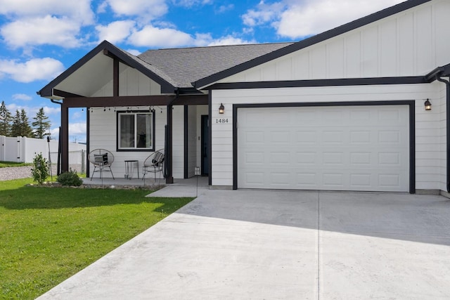 ranch-style home featuring a front lawn, driveway, board and batten siding, covered porch, and an attached garage