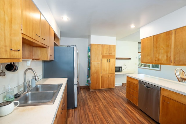 kitchen featuring stainless steel appliances, a sink, dark wood finished floors, light countertops, and recessed lighting