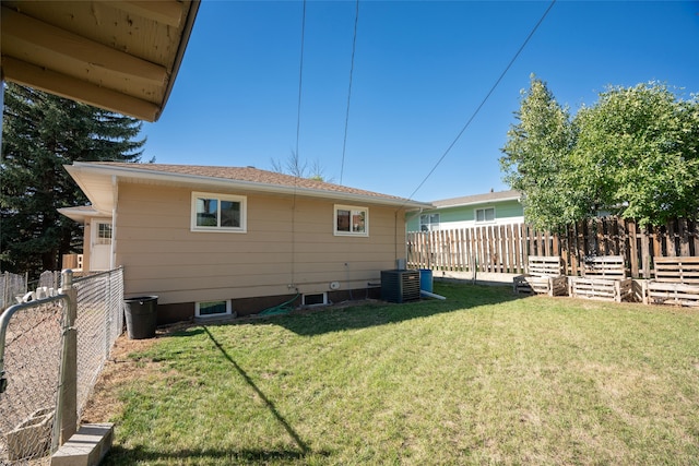 rear view of property featuring a yard and central AC