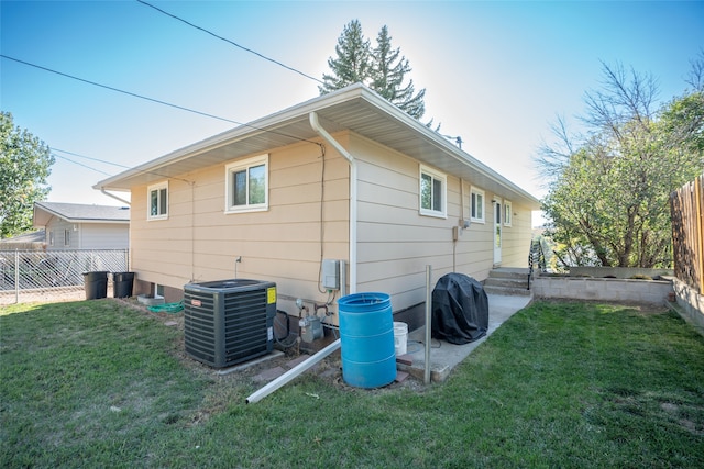 back of house featuring a lawn and central air condition unit