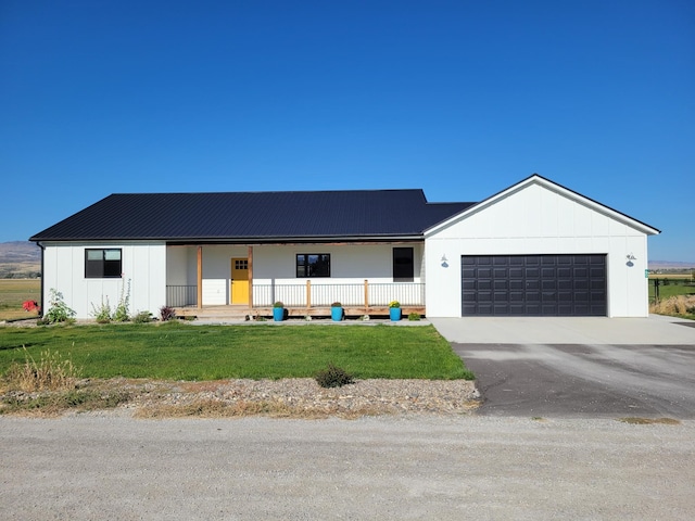 modern inspired farmhouse featuring a front lawn, covered porch, and a garage