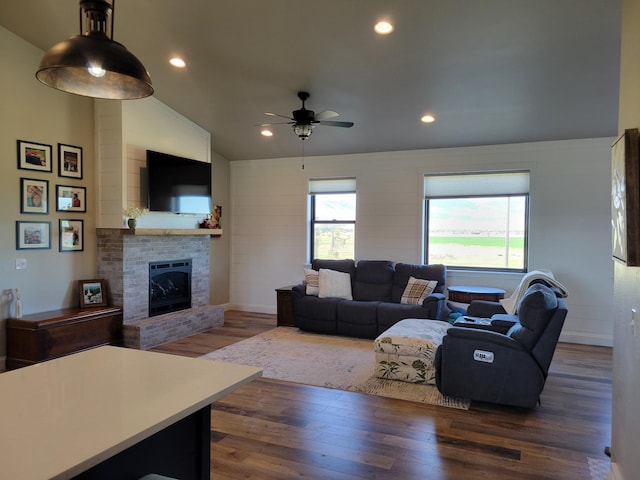 living room with vaulted ceiling, ceiling fan, dark hardwood / wood-style floors, and a fireplace