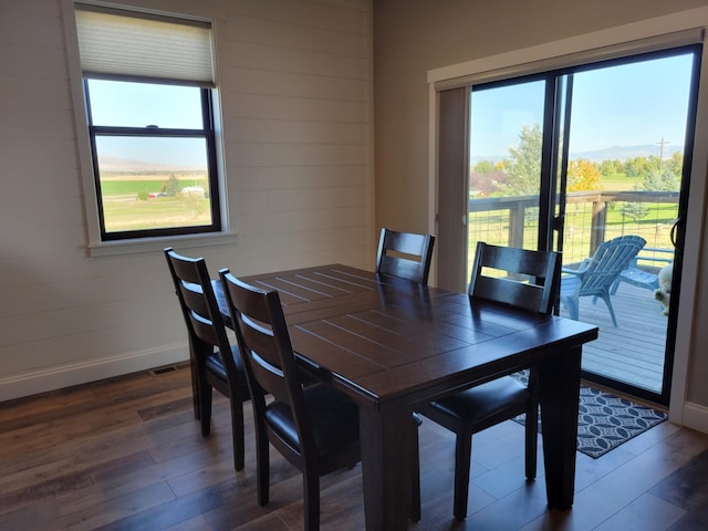 dining area featuring wood walls and dark wood-type flooring