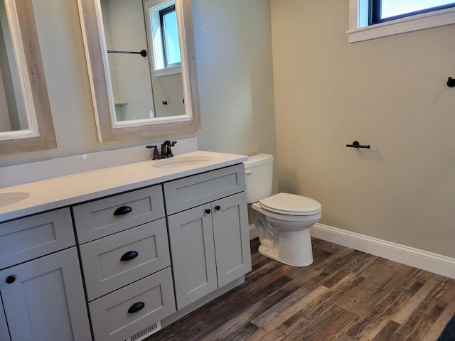 bathroom featuring wood-type flooring, vanity, toilet, and a healthy amount of sunlight