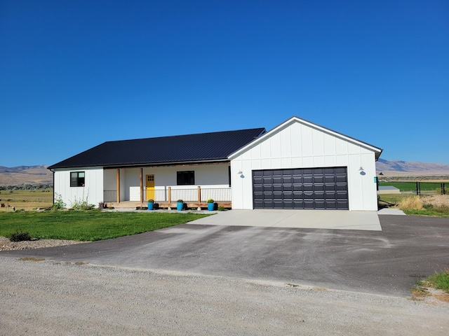 modern farmhouse featuring a mountain view, a front lawn, and a garage