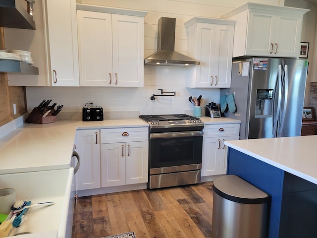 kitchen with white cabinets, appliances with stainless steel finishes, and wall chimney range hood