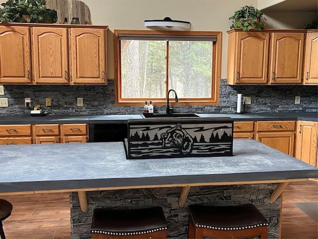 kitchen with hardwood / wood-style flooring, sink, a breakfast bar area, and backsplash