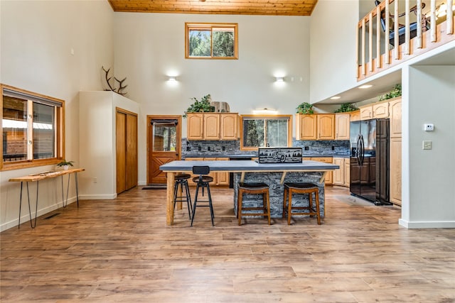 155 Grandview Ln, Seeley Lake, MT 59868 - kitchen featuring black fridge with ice dispenser, high vaulted ceiling, a kitchen island, a breakfast bar area, and healthy amount of natural light