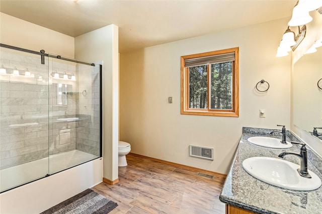 155 Grandview Ln, Seeley Lake, MT 59868 - bathroom featuring toilet, wood finished floors, baseboards, double vanity, and enclosed tub / shower combo