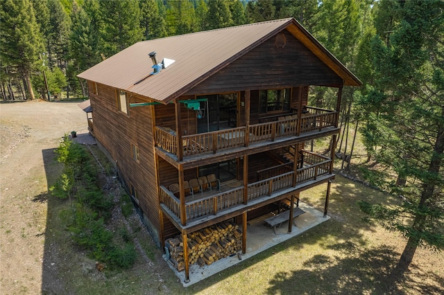 155 Grandview Ln, Seeley Lake, MT 59868 - rear view of house featuring a wooden deck, a view of trees, metal roof, and a patio area