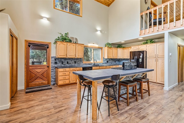 155 Grandview Ln, Seeley Lake, MT 59868 - kitchen with high vaulted ceiling, black appliances, light brown cabinetry, and light wood-style flooring
