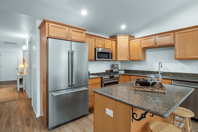 kitchen featuring light hardwood / wood-style flooring, lofted ceiling, a center island, and high quality appliances