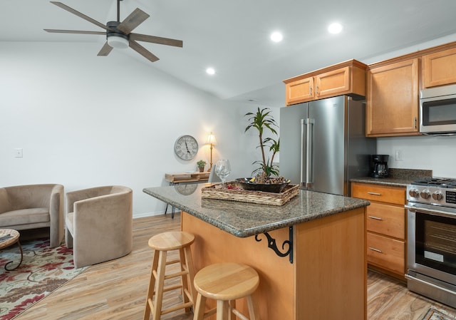 kitchen with vaulted ceiling, a center island, stainless steel appliances, a breakfast bar, and light hardwood / wood-style floors