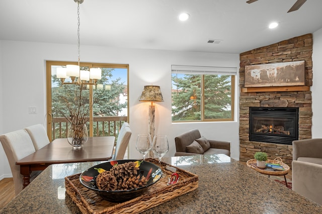 dining space with wood-type flooring, ceiling fan with notable chandelier, a fireplace, and lofted ceiling