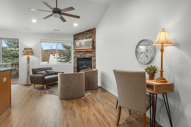 living room featuring vaulted ceiling, ceiling fan, plenty of natural light, and a stone fireplace